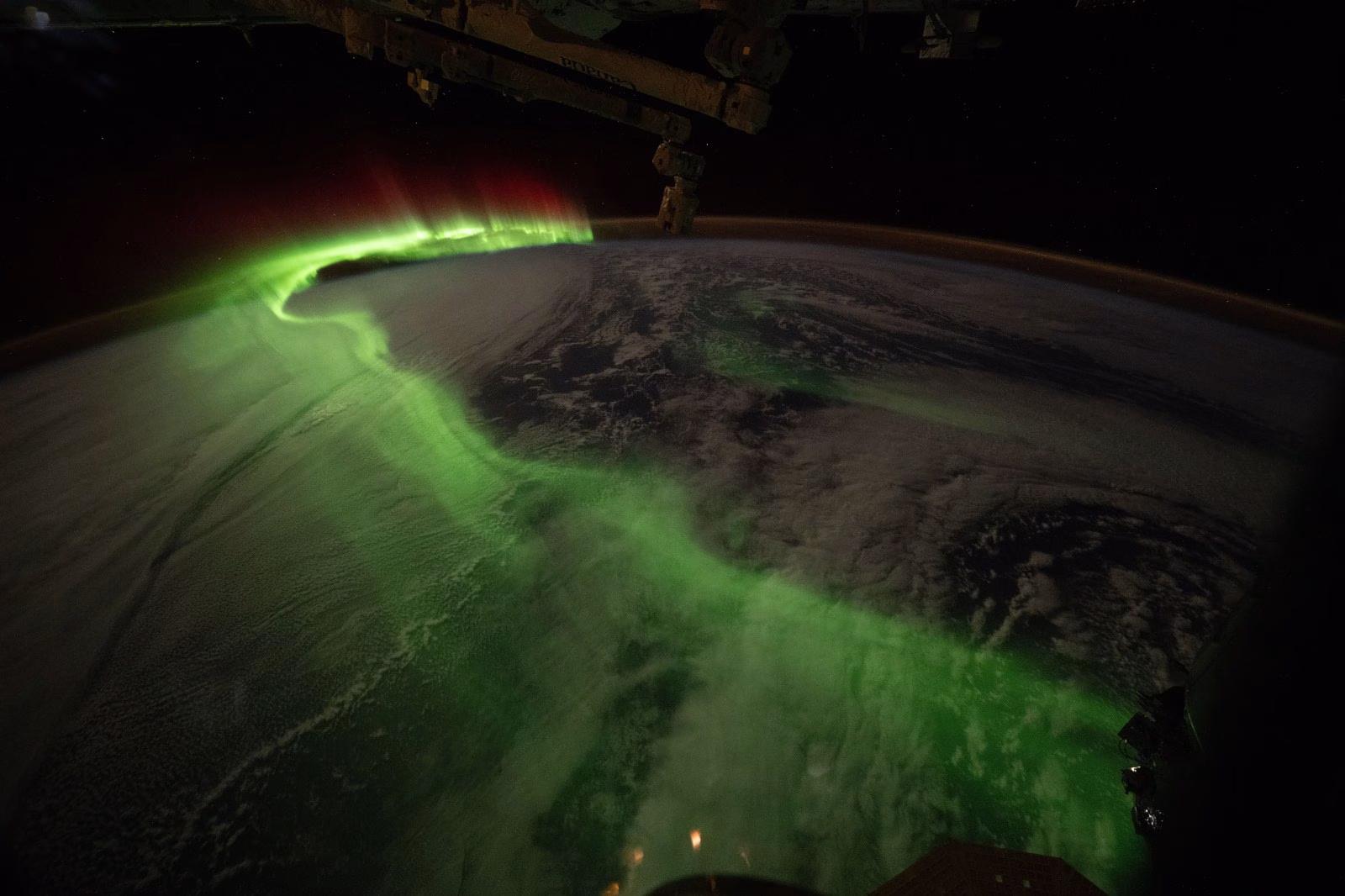 Green southern aurora curving over Earth's dark horizon, photographed from the ISS in June 2026
